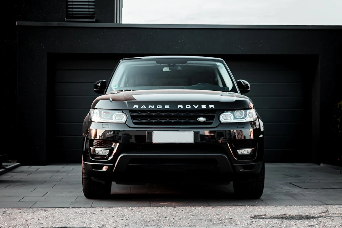 Dark Range Rover Sport photographed from the front three-quarter on a wet road.