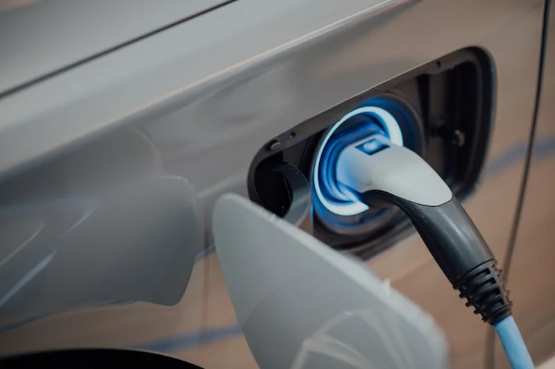 Charging cable plugged into the charge port of a silver electric car.